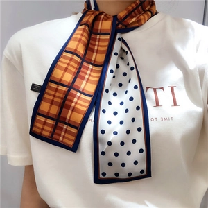 Detail of a double-sided skinny silk scarf with orange plaid and blue polka dots pattern
