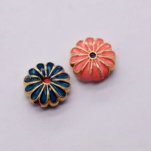 Detailed macro view of daisy enamel flower charms in navy blue and orange pink with gold borders