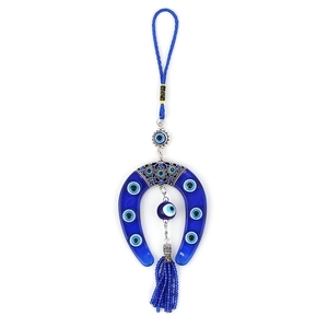 Macro shot of glass Evil Eye horseshoe hanging ornament with blue beaded tassel detail