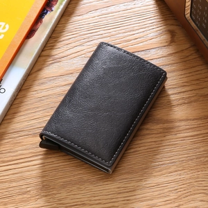 Slim black leather RFID blocking credit card holder on a wooden office desk surface