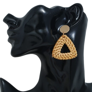 Détail de boucles d'oreilles triangulaires en rotin avec disque doré sur mannequin noir