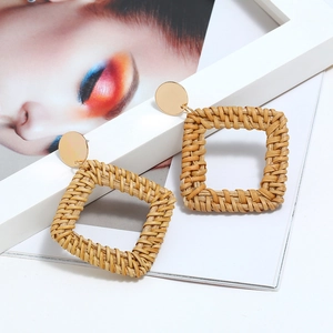 Détail de boucles d'oreilles carrées en rotin fait main avec clous en métal doré