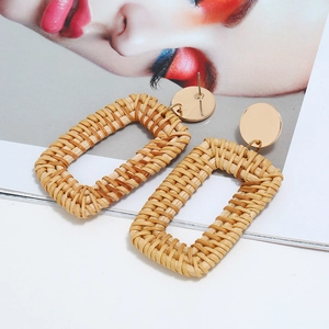 Détail de boucles d'oreilles carrées en rotin tressé avec disque en métal doré