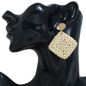 Détail de boucles d'oreilles carrées en rotin tressé avec disque doré sur mannequin