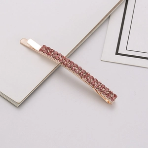 Detail of rose gold hair clip with double row pink rhinestones on book background