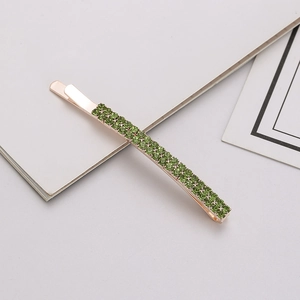 Detail shot of rectangular rose gold hair clip with double rows of green rhinestones