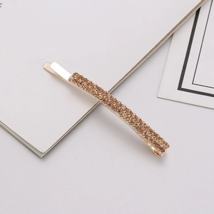 Detailed close-up of a golden hair clip with two rows of sparkling champagne rhinestones