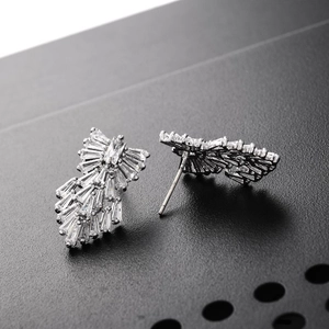 Macro shot of silver feather earrings with AAA zircons on black surface