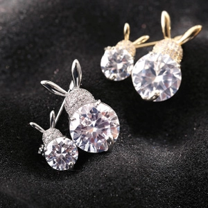 Close-up of rabbit-shaped stud earrings in gold and silver with sparkling cubic zirconia