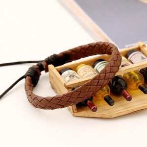 Close-up of brown woven leather bracelet with adjustable pull cord on a minimalist stand