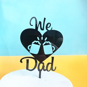 Detail of black acrylic 'We Dad' cake topper featuring heart shape and beer mugs design