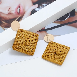 Détail de boucles d'oreilles en rotin tressé à la main avec disque en métal doré