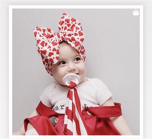 Close-up of red heart print large bow headband worn by baby for festive style