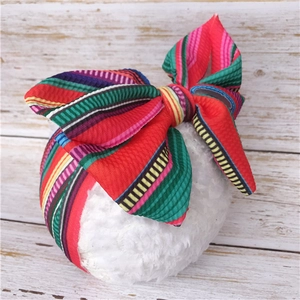 Detail of baby headband featuring multi-colored stripe pattern and oversized soft bow