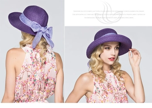 Detail of a purple straw sun hat featuring a large flaxen bow and fine woven texture