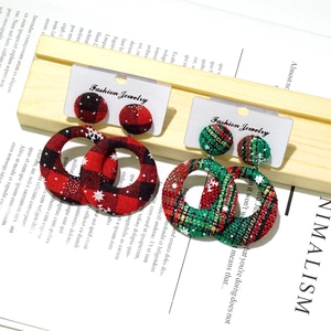 Detail of Christmas plaid fabric button earrings in red and green on a wooden stand