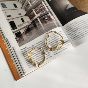 Detailed view of gold spiral hoop earrings with delicate butterfly motifs on magazine