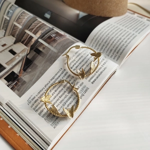 Detailed close-up of S925 sterling silver stamp on golden braided butterfly hoop earrings