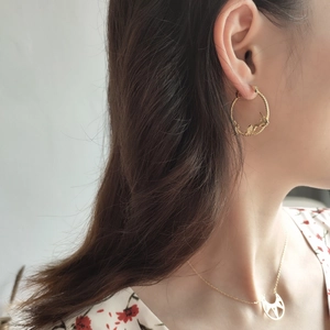 Detail of vintage woven gold floral earrings and necklace on model with warm tones