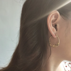 Vintage golden hoop earrings with embossed butterfly and leaf patterns on a model