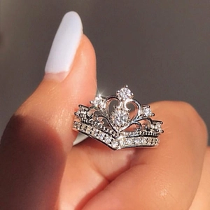 Detail of zircon crown ring with heart design and silver plating worn on finger