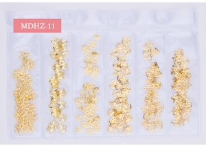 Detailed view of six gold metallic nail art charms including snowflakes and shells