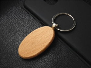 Close-up of an oval beech wood keychain with silver metal ring on black leather