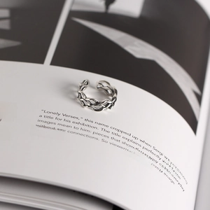 Artistic close-up of a silver Mobius twist wave ring resting on open book pages