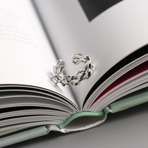 Macro shot of a layered silver braided ring on a book page with vintage aesthetics