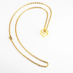 Minimalist gold hollow cube pendant necklace in polished titanium steel on white background