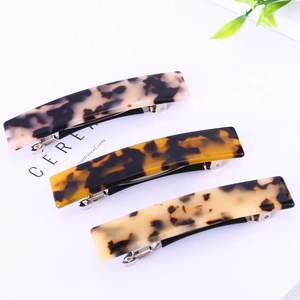 Three acetate hair clips in tortoiseshell and ink patterns on a white minimalist background