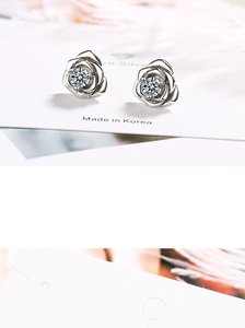 Detailed view of silver rose stud earrings with a sparkling central crystal on a card