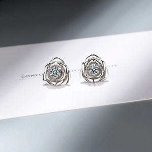 Elegant silver rose stud earrings with sparkling zircon centers on a white display card