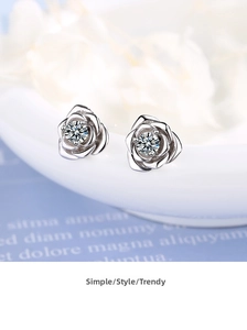 Macro detail of silver rose stud earrings with cubic zirconia and matte petals