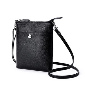 Detail of black textured leather mini shoulder bag with silver hardware and front pocket