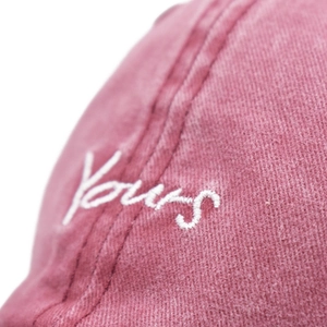 Close-up of Yours embroidery on washed cotton baseball cap with vintage texture detail