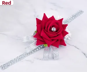Detail of a red artificial rose wrist corsage with sparkling rhinestone chain and silver ribbon