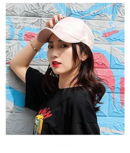 Close-up of pink camouflage baseball cap worn by female model against graffiti wall