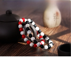 Three-color beaded bracelet with matte black, white turquoise and red stones on a teapot