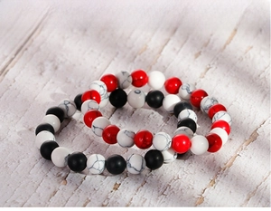 Detail of 8mm matte black agate and white turquoise beaded bracelets on wood background