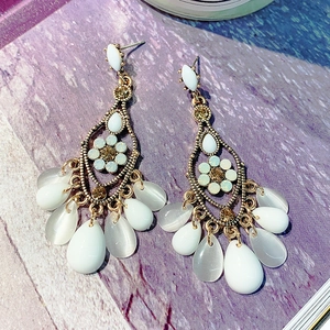 Detail of vintage bronze long earrings with white teardrop stones and rhinestones