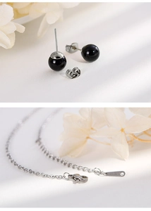 Close-up of stainless steel jewelry set including black stud earrings and necklace
