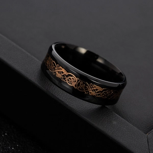 Macro shot of black titanium steel ring with rose gold celtic dragon pattern inlay