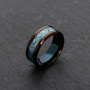 Macro shot of black titanium steel ring with silver dragon inlay and blue carbon fiber