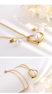 Detail view of heart-shaped gold necklace and pearl earrings set with floral accents