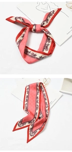 Detail of pink silk scarf with red border and stylized patterns tied in a bow