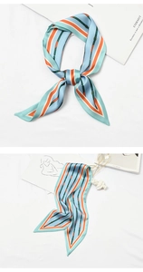 Detailed view of a light blue silk scarf with orange stripes and artistic floral print