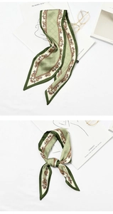 Detail of green silk scarf featuring golden chain and horsebit patterns with glasses