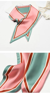 Detailed macro view of the smooth pink and green striped silk texture on the scarf surface
