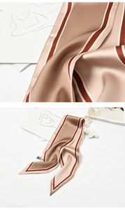 Close-up of beige silk scarf with red and white stripes displayed on a white surface